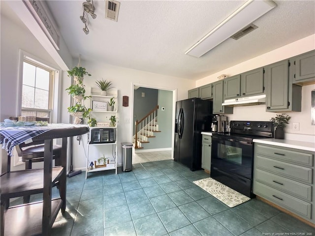 kitchen with black appliances, dark tile patterned floors, and a textured ceiling