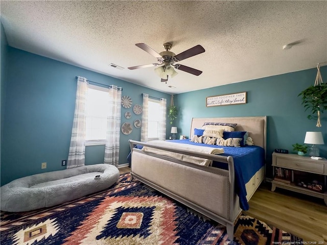 bedroom featuring wood-type flooring, a textured ceiling, and ceiling fan