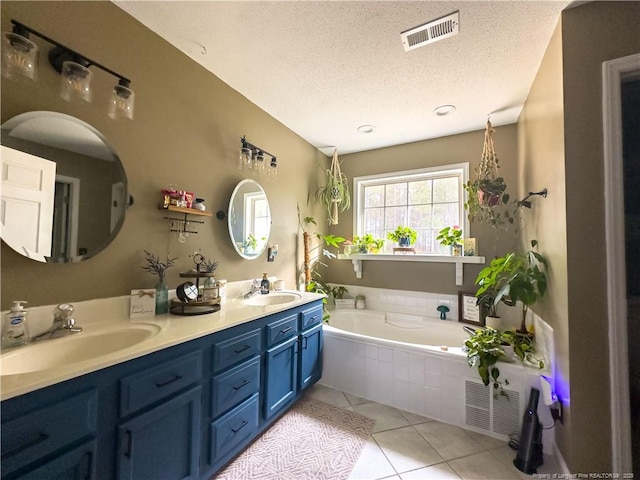 bathroom with vanity, tile patterned floors, a relaxing tiled tub, and a textured ceiling