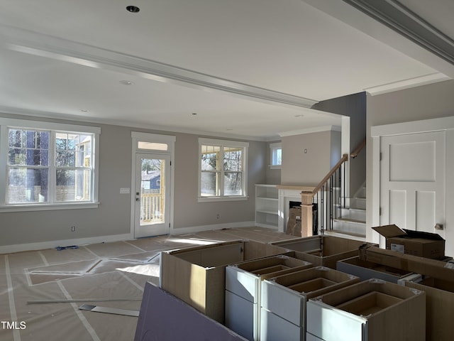 unfurnished living room with baseboards, a healthy amount of sunlight, a fireplace, and crown molding