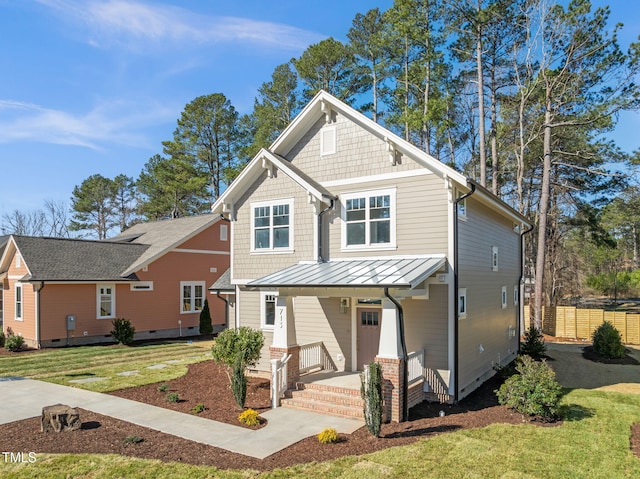 craftsman-style home featuring a front lawn, a standing seam roof, fence, covered porch, and metal roof