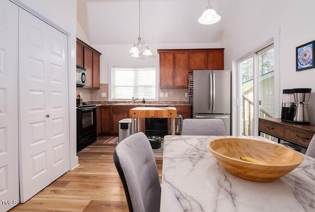 kitchen with black appliances, decorative backsplash, a wealth of natural light, and hanging light fixtures