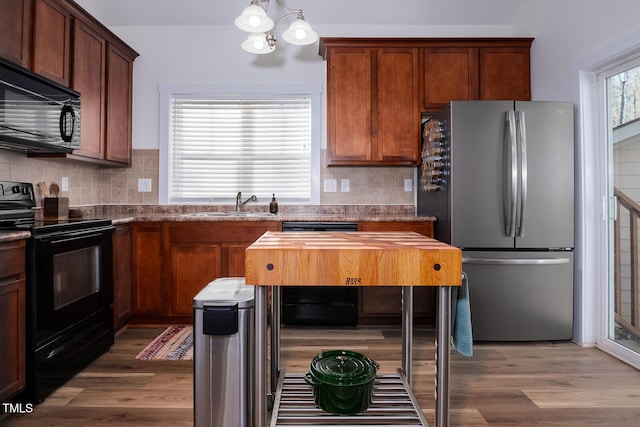 kitchen featuring black appliances, dark hardwood / wood-style flooring, an inviting chandelier, sink, and backsplash