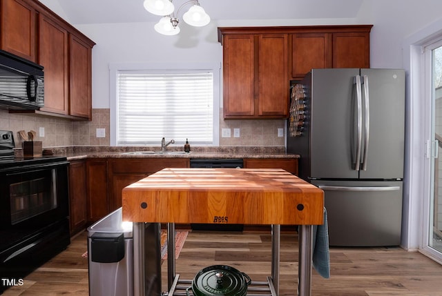 kitchen featuring black appliances, decorative backsplash, wooden counters, and sink