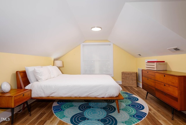 bedroom with vaulted ceiling and hardwood / wood-style floors