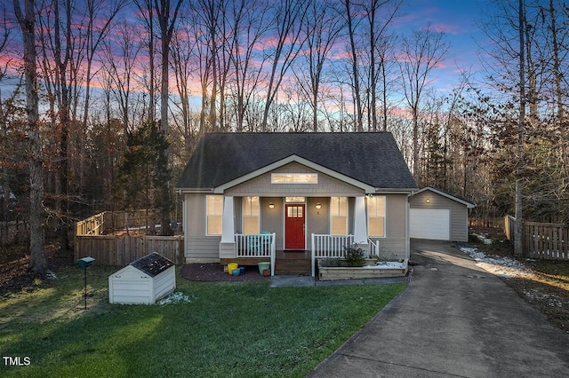 view of front of house with covered porch, a garage, an outbuilding, and a yard