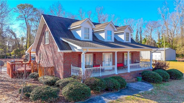 cape cod home with covered porch and a storage shed