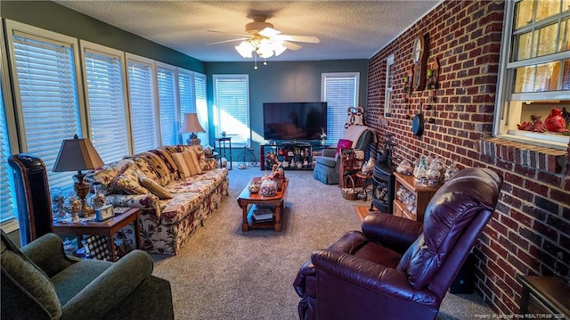 carpeted living room with ceiling fan, a textured ceiling, and brick wall