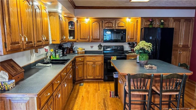 kitchen with sink, a kitchen breakfast bar, light hardwood / wood-style floors, black appliances, and a kitchen island