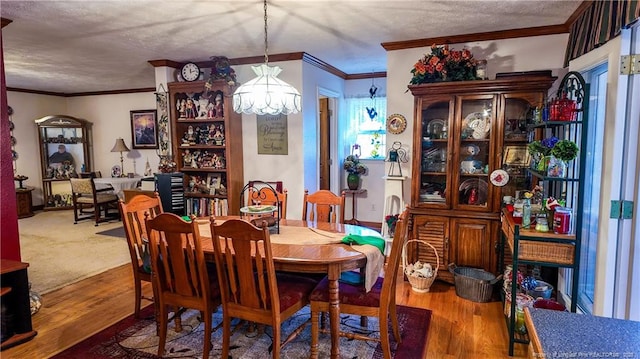 dining space with hardwood / wood-style flooring, ornamental molding, and a textured ceiling