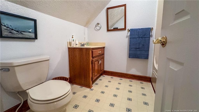 bathroom featuring vanity, toilet, vaulted ceiling, and a textured ceiling