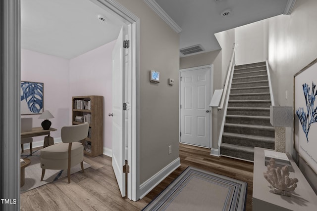 stairs with hardwood / wood-style floors and crown molding