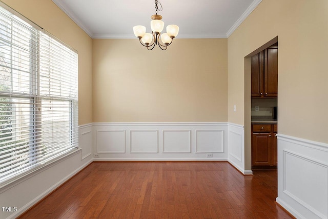 unfurnished dining area featuring a notable chandelier, plenty of natural light, dark hardwood / wood-style flooring, and ornamental molding