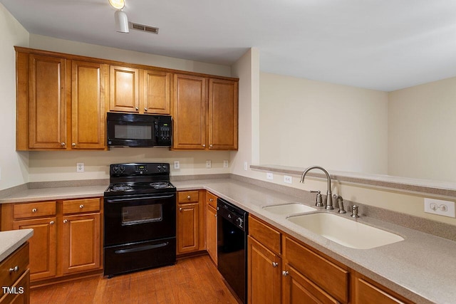 kitchen featuring sink, black appliances, and light hardwood / wood-style flooring