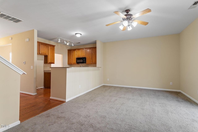 kitchen with carpet, rail lighting, kitchen peninsula, and ceiling fan