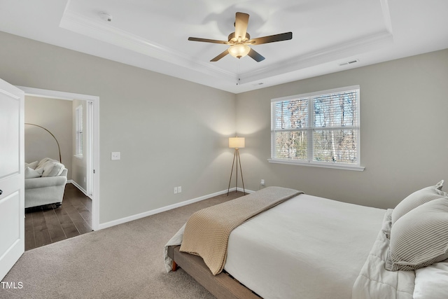 carpeted bedroom featuring ceiling fan and a tray ceiling