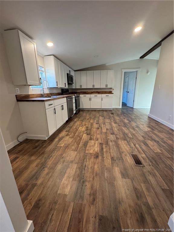 kitchen featuring lofted ceiling, dark hardwood / wood-style flooring, white cabinetry, appliances with stainless steel finishes, and sink