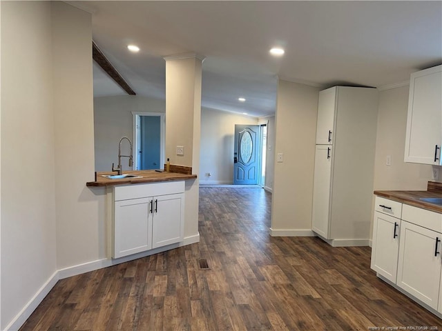 kitchen featuring sink, dark wood-type flooring, white cabinetry, and butcher block counters