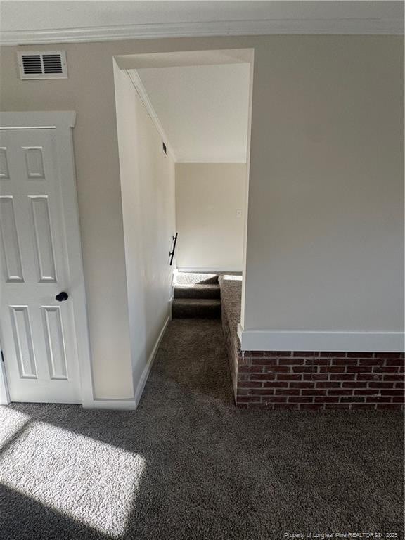 corridor with crown molding and dark carpet