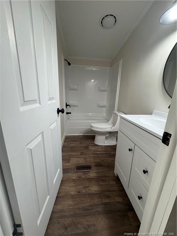 full bathroom featuring toilet, hardwood / wood-style flooring, shower / washtub combination, ornamental molding, and vanity