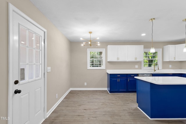 kitchen with blue cabinets, white cabinetry, sink, hanging light fixtures, and light wood-type flooring