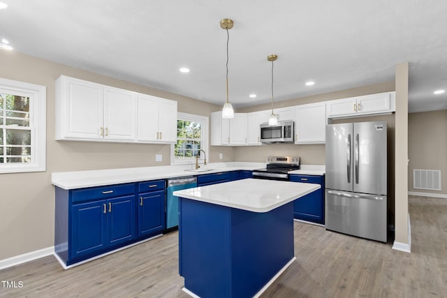 kitchen with appliances with stainless steel finishes, decorative light fixtures, sink, a center island, and blue cabinetry