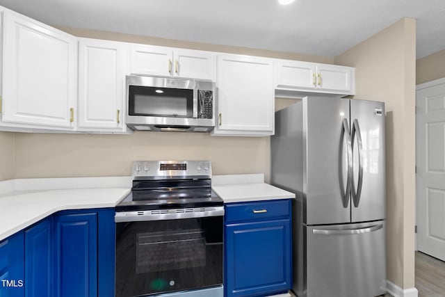 kitchen with stainless steel appliances, blue cabinets, white cabinets, and light hardwood / wood-style floors