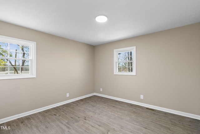 spare room with plenty of natural light and wood-type flooring