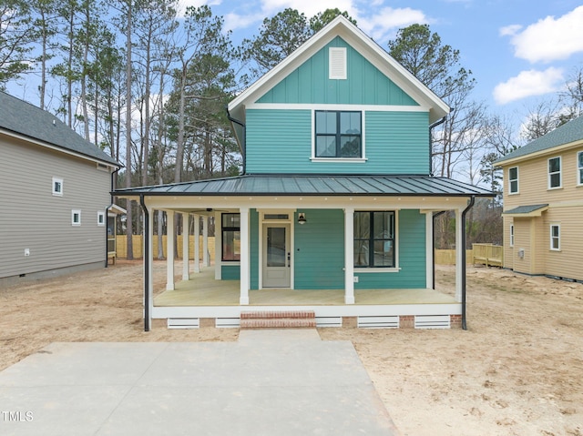 view of front of property with covered porch, board and batten siding, driveway, and a standing seam roof