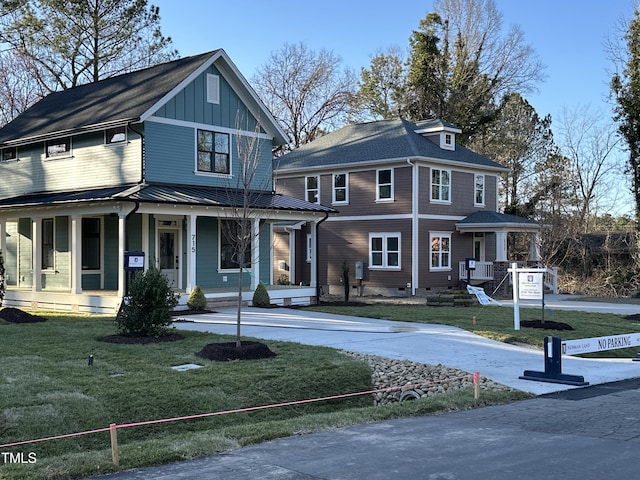 view of front of property featuring driveway, a standing seam roof, a porch, board and batten siding, and a front yard