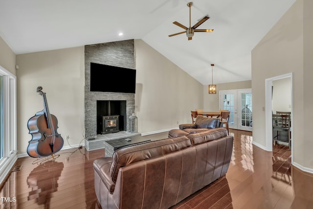 living room featuring lofted ceiling, ceiling fan, a wood stove, and hardwood / wood-style flooring