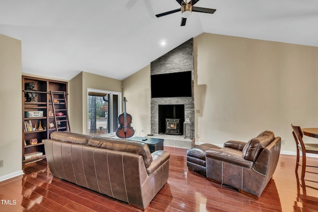 living room with vaulted ceiling, ceiling fan, a wood stove, and hardwood / wood-style floors