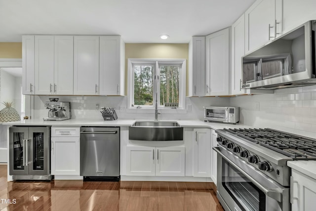 kitchen featuring wine cooler, sink, stainless steel appliances, and white cabinetry