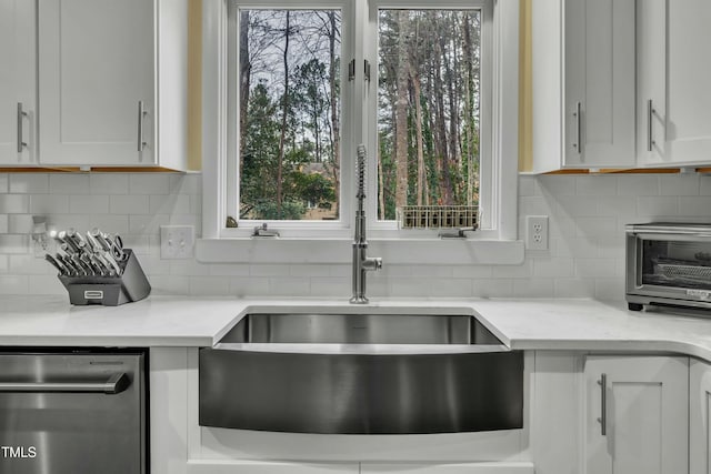 kitchen with white cabinets, backsplash, sink, and light stone counters