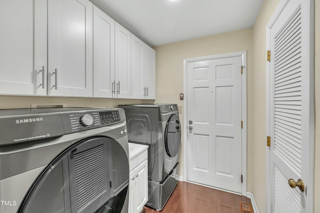 laundry area with washing machine and dryer, cabinets, and dark hardwood / wood-style flooring