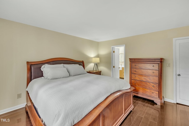 bedroom with ensuite bathroom and dark wood-type flooring