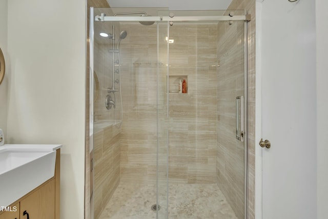 bathroom featuring a shower with door and vanity