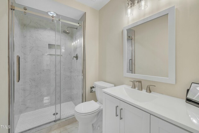 bathroom featuring toilet, a shower with shower door, and vanity