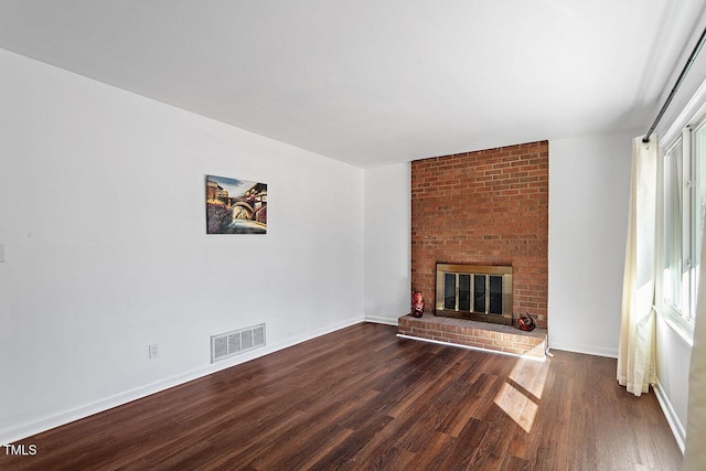 unfurnished living room with dark wood-type flooring, a wealth of natural light, and a fireplace