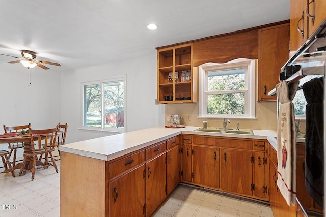 kitchen with a wealth of natural light, decorative backsplash, kitchen peninsula, and sink