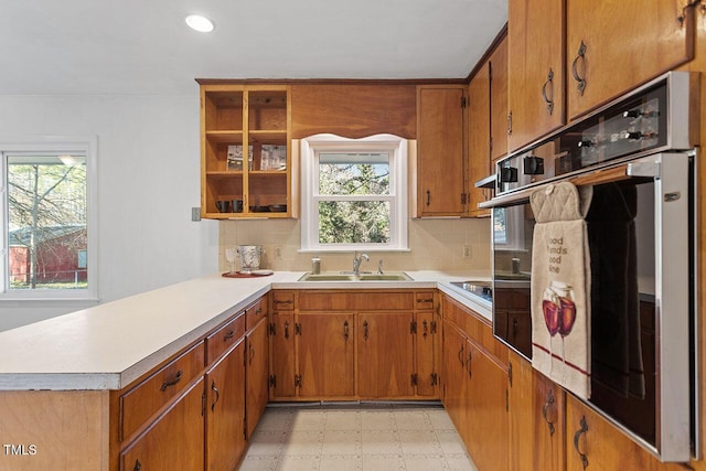 kitchen with oven, a healthy amount of sunlight, kitchen peninsula, and sink