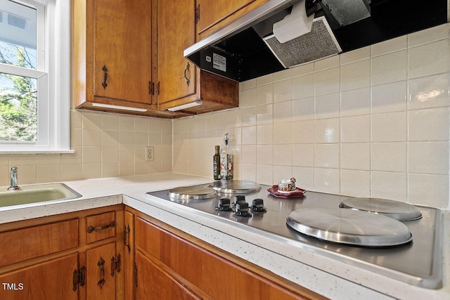 kitchen with decorative backsplash, sink, extractor fan, and electric cooktop