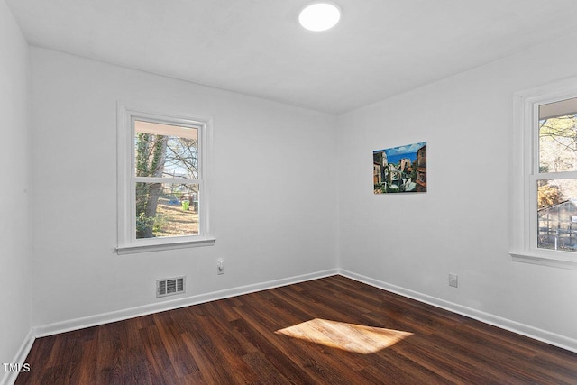 empty room with plenty of natural light and dark hardwood / wood-style floors