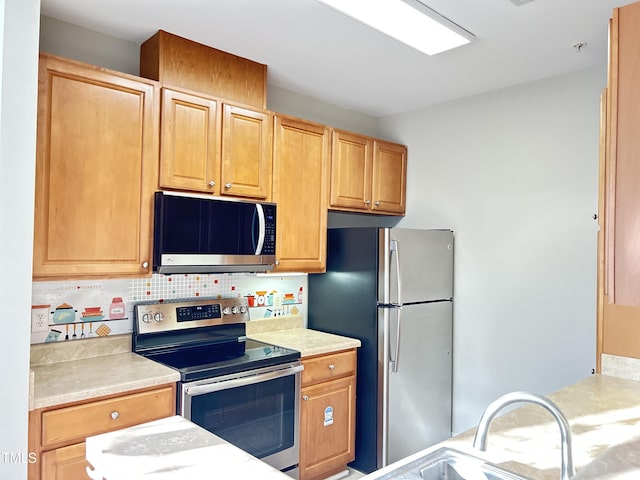 kitchen featuring decorative backsplash, appliances with stainless steel finishes, and sink