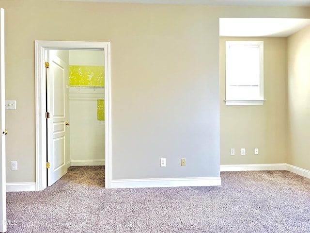 unfurnished bedroom featuring a closet, carpet, and a walk in closet