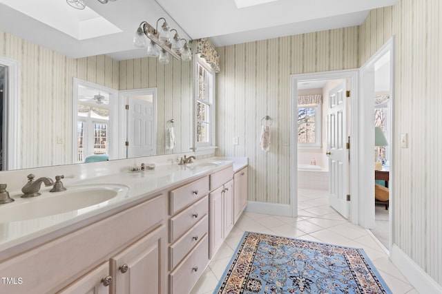 bathroom featuring a relaxing tiled tub, tile patterned flooring, a skylight, vanity, and ceiling fan