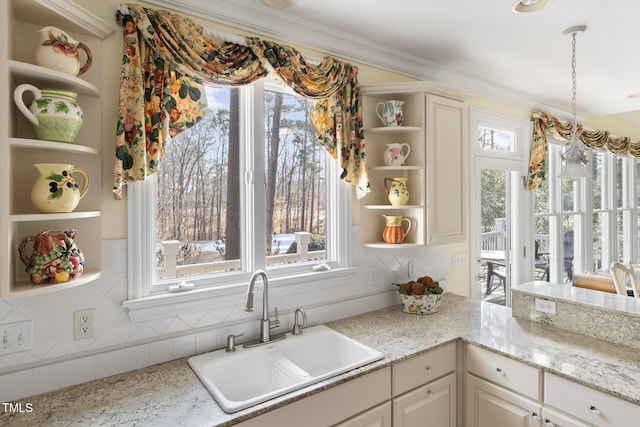 kitchen with sink, crown molding, a wealth of natural light, and light stone counters