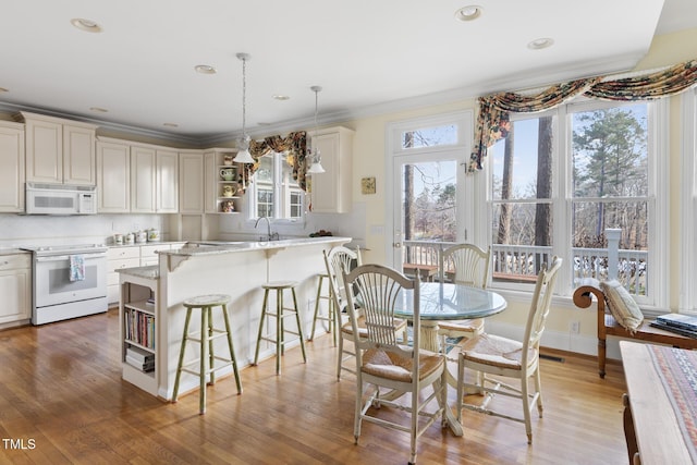 dining space featuring ornamental molding, light hardwood / wood-style floors, and sink