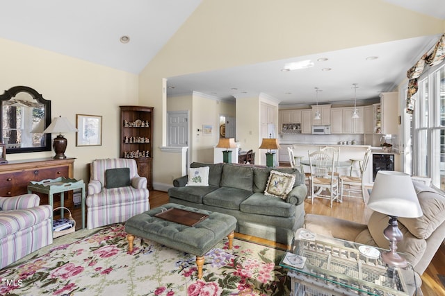 living room with light hardwood / wood-style floors, ornamental molding, high vaulted ceiling, and wine cooler