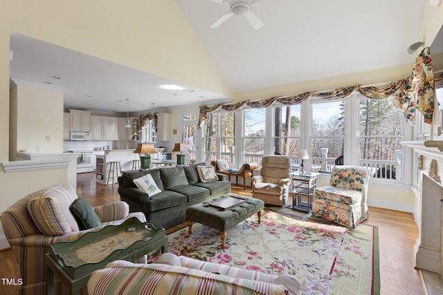 living room with vaulted ceiling, a fireplace, ceiling fan, and light hardwood / wood-style flooring